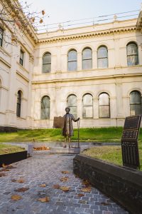 Bronze Sculture of a woman holding a protest sign and a chain with a Historic Building in the background