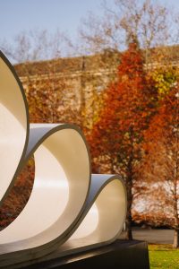 A Scroll like sculpture with red Autumn tree in the background