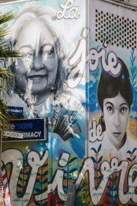 The corner of a building with a Mural of a Young woman on one wall and Mature woman on the other wall