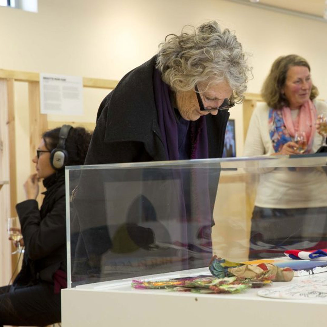 A woman peers through glass to view an exhibition object.