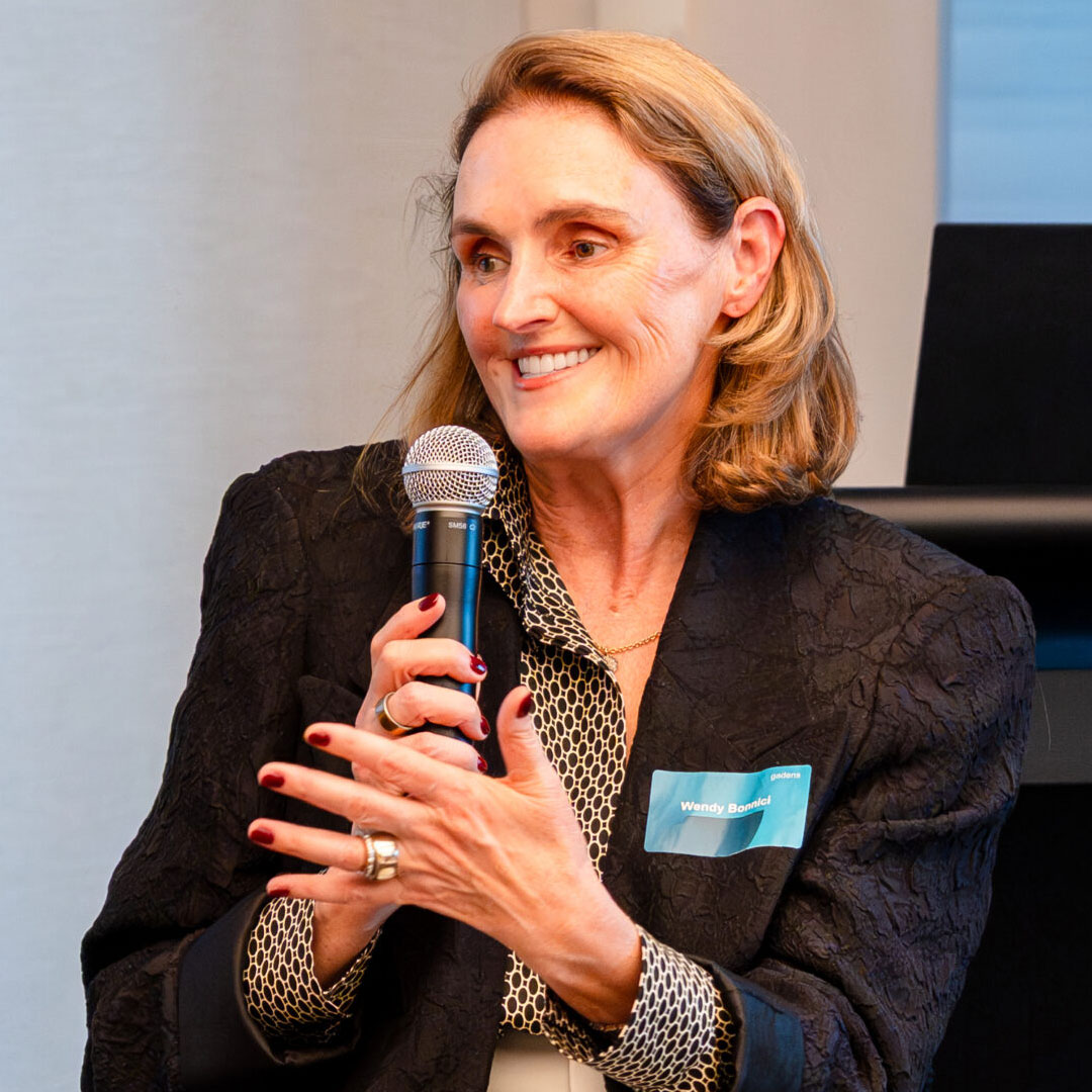 A smiling woman holds a microphone to her face.