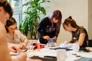 Four individuals leaning over a table.
