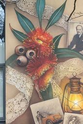 The side of a building decorated with a mural of a Woman at a deak writing surrounded by native flowers and